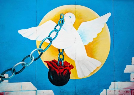 Dove of peace in front of sun carries chain with weight