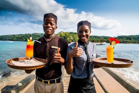 Waiters serving cocktails on a long wooden pier in the Bom Bom Resort