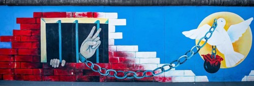 Mural Angekettete Hand makes peace sign from prison with peace dove