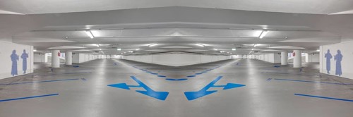 Photomontage of an empty underground car park with blue arrows on the ground