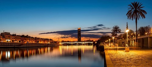 View over the river Rio Guadalquivir with illuminated bridge Puente de Triana and promenade