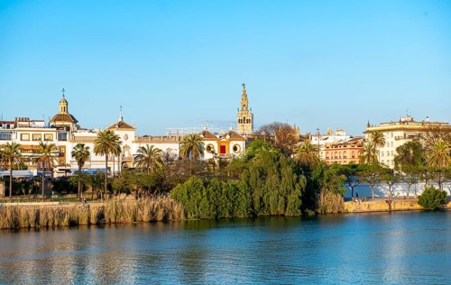 View over the river Rio Guadalquivir to the bullring Plaza de toros de la Real Maestranza de Caballeria de Sevilla and bell tower La Giralda