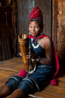 Old Kayah woman playing local instrument