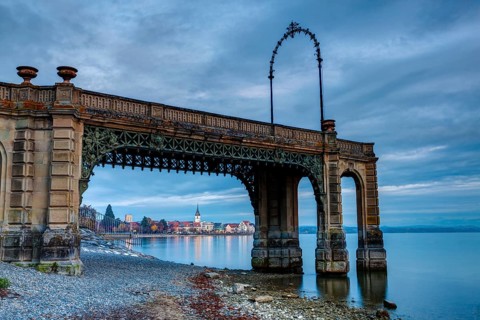 Castle footbridge after sunset and Friedrichshafen in the distance
