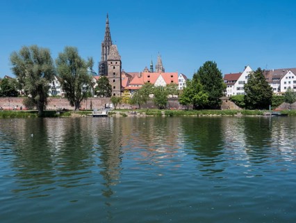 Ulm Cathedral and buildings on the banks of the Danube with water reflection