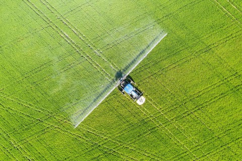 Tractor spraying fungicide onto the rice fields