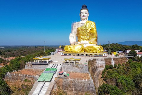 Aerial of a giant sitting buddha below the Kyaiktiyo Pagoda