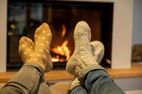 Feet with cuddly socks in front of a fireplace