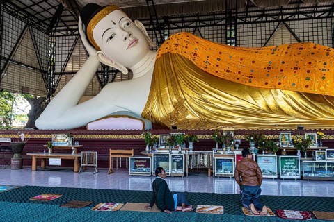 Pilgrims praying before a reclining buddha