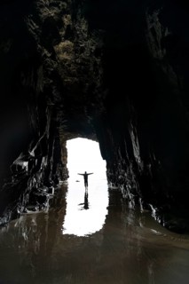 Silhouette of a person in front of cave exit in backlight