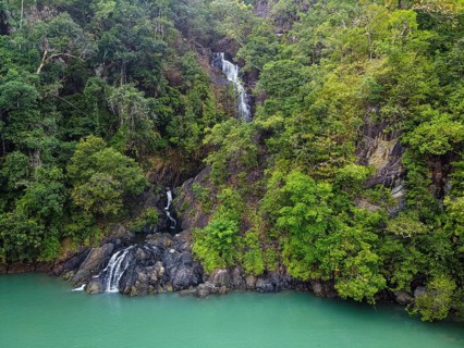 Aerial of a waterfall dropping right in the ocean on Dome island