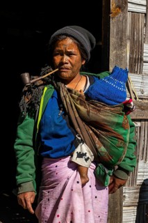 Chin woman with spiderweb tattoo smoking a pipe