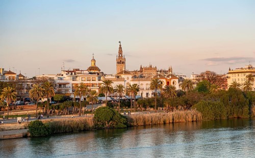 View over the river Rio Guadalquivir to the bullring Plaza de toros de la Real Maestranza de Caballeria de Sevilla and bell tower La Giralda
