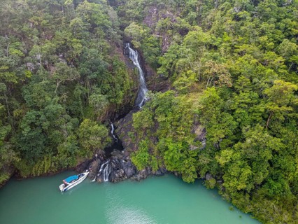 Aerial of a waterfall dropping right in the ocean on Dome island