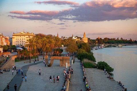 Waterfront promenade Muelle de la sal at the river Rio Guadalquivir with Monumento a la Tolerancia and Torre del Oro