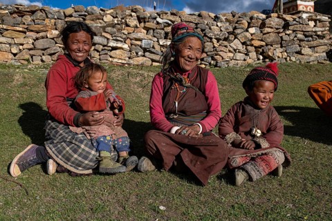 Women and children sitting in the evening sun in a meadow