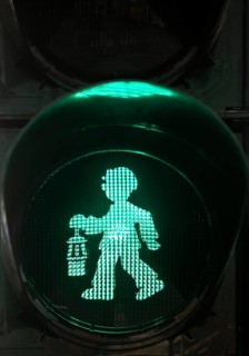Green pedestrian traffic light man as miner with pit lamp