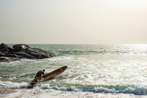 Man mounts his dugout canoe on the ocean east of Buchanan