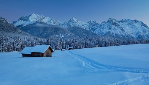 Winterly hummock meadows with hay barn and Karwendel mountains at dusk