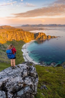 Hiker standing on a rocky outcrop overlooking beach and sea