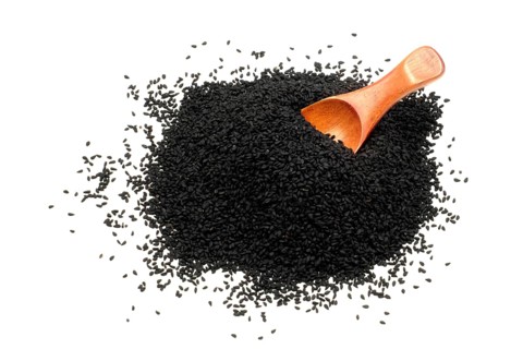 Nigella seeds with a wooden spoon against a white background