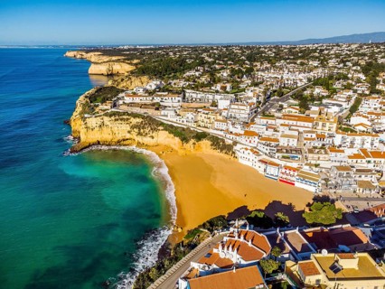 Aerial view of wide sandy beach and traditional architecture of Carvoeiro in Algarve