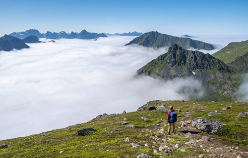 Hiker looking over mountain landscape in clouds