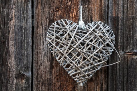 Woven heart hanging on an old wooden facade made of weathered wood