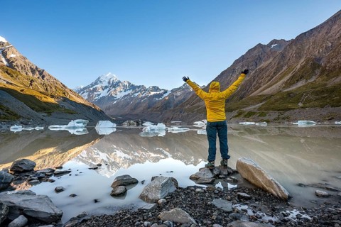 Hiker at the lake stretching her arms in the air