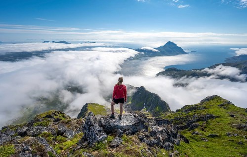 Hiker looking over mountain landscape in clouds