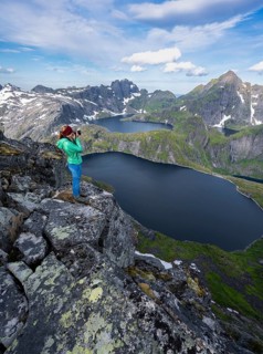 Young woman photographing mountain landscape with lake Tennesvatnet and Krokvatnet