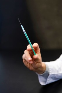 A hand holds a syringe for vaccine against COVID-19 at a vaccination center in Erding