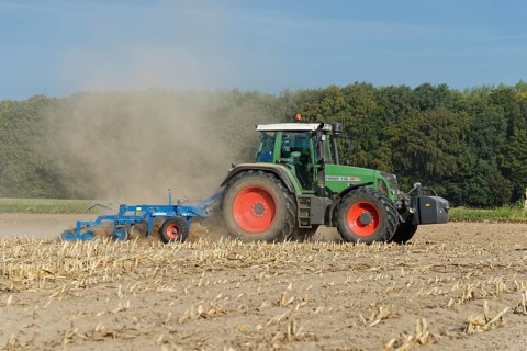 Farmer cultivating harvested maize field