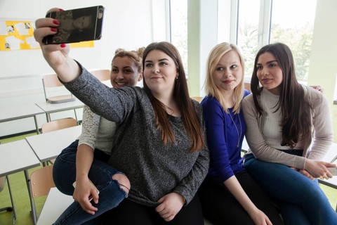 Vocational school students with their smartphones during break at the Elly-Heuss-Knapp-Schule