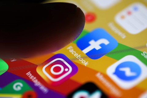 Finger about to press on the Facebook app icon on a smartphone