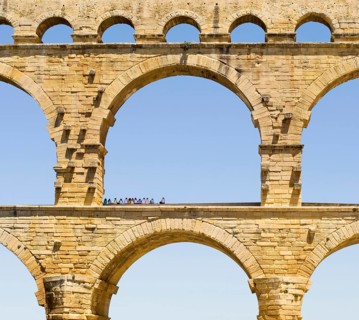 A group of tourists resting in the shadow of the Pont du Gard