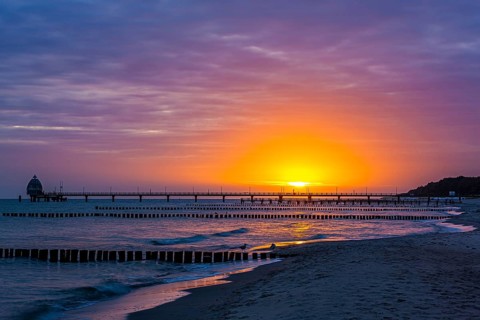 Groyne and diving gondola with pier at the beach of Zingst at sunrise