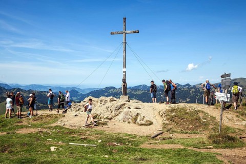 Hiker at the summit cross at Riedberger Horn