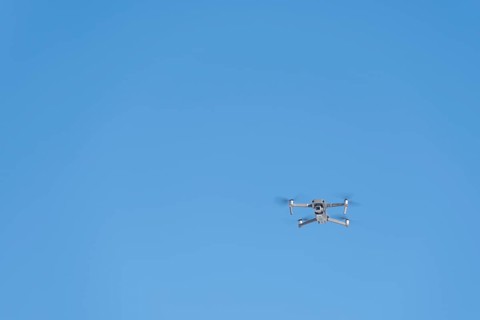 Drone flies in front of blue sky