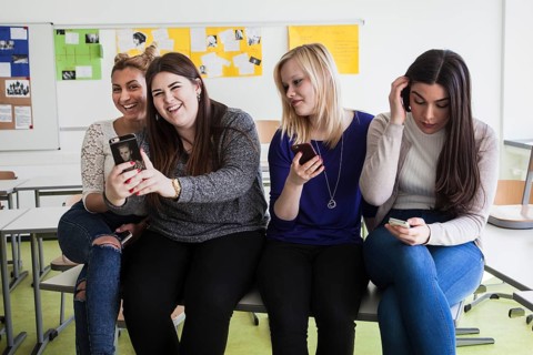 Vocational school students with their smartphones during break at the Elly-Heuss-Knapp-Schule