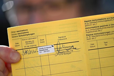 Woman proudly showing her vaccination certificate after being vaccinated with AstraZeneca against Covid-19