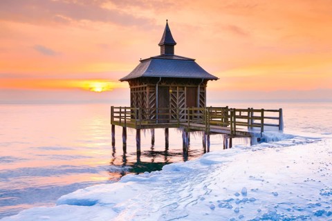 Iced wooden bathhouse at sunrise on Lake Neuchatel in Gorgier