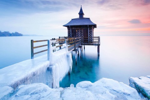 Iced wooden bathhouse at sunrise on Lake Neuchatel in Gorgier