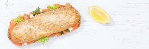 Sandwich baguette wholemeal roll topped with salmon fish banner text free space from top on
