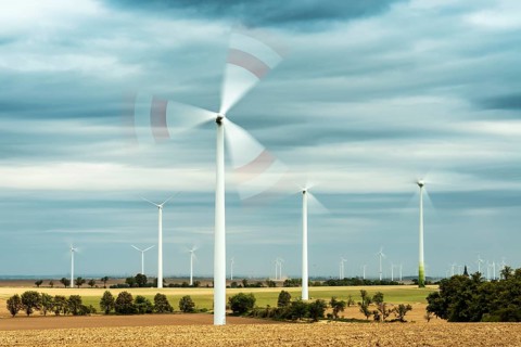 Field landscape with rotating wind turbines
