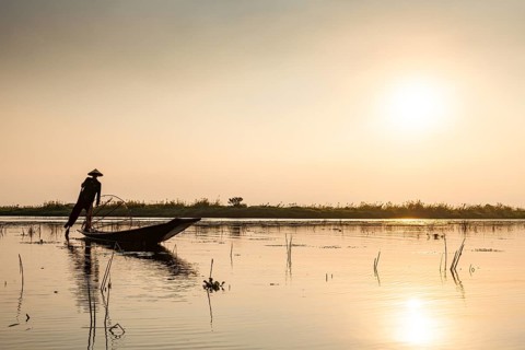 Fisherman at Inle Lake with traditional Intha conical net at sunset