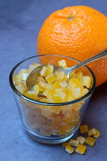 Candied orange peel cubes in glass with spoon