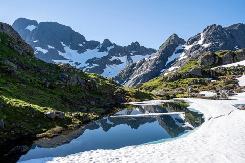 Mountains reflected in the lake Isvatnet with ice