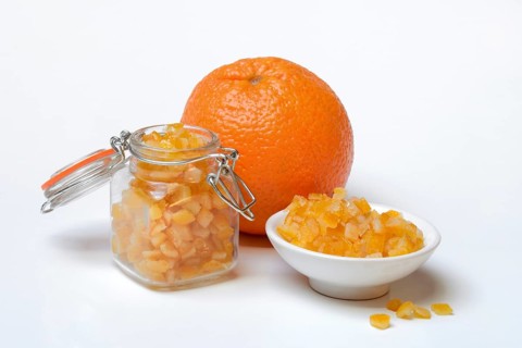 Candied orange peel cubes in glass and peel