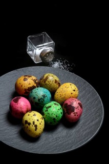 Colored quail eggs on plate and salt shaker